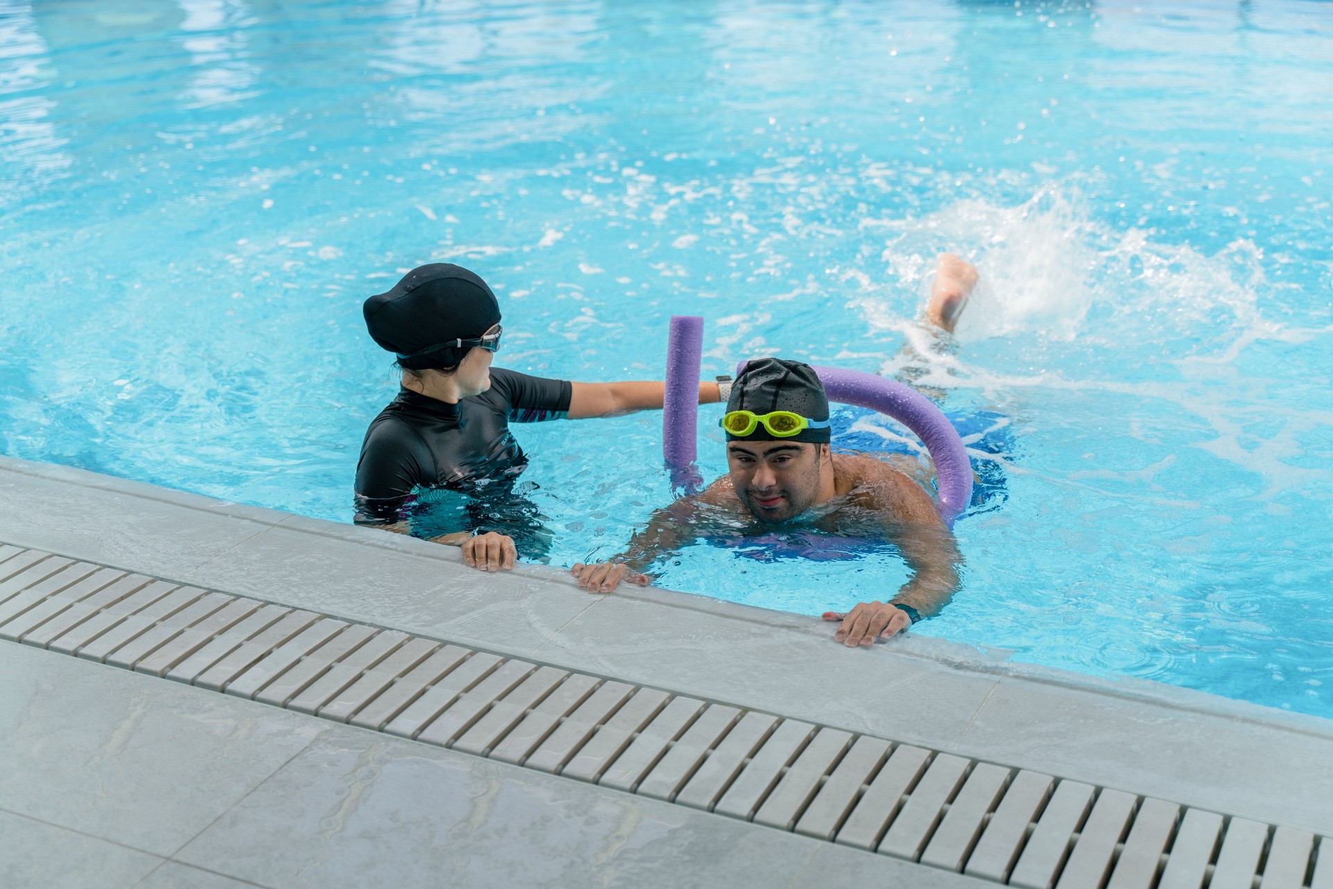 Female Coach  Giving boy  with down syndrome, Swimming Lesson In Indoor Pool in the swimming pool